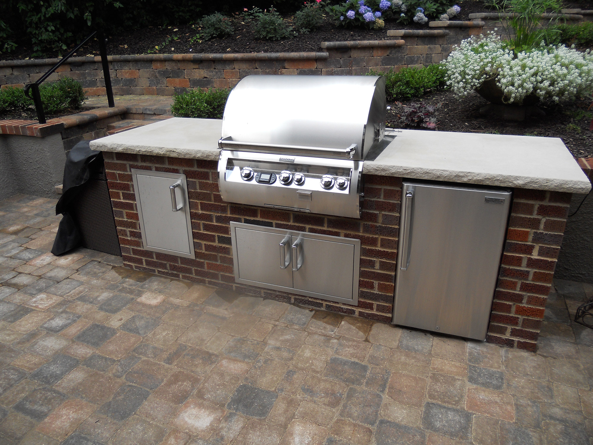 Built-in outdoor kitchen with a stone counter built by Outlook Hardscape
